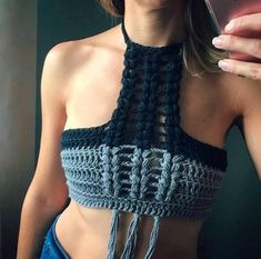 a woman wearing a crochet halter top holding a cell phone