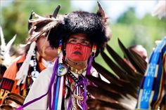 a native american man with feathers on his head and other people in costume behind him