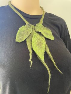 a woman wearing a black shirt with green leaves on it