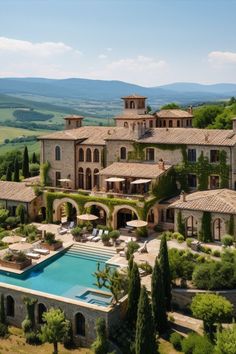 an aerial view of a large house with a pool in the foreground and mountains in the background