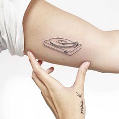 a woman's arm with a record player tattoo on it