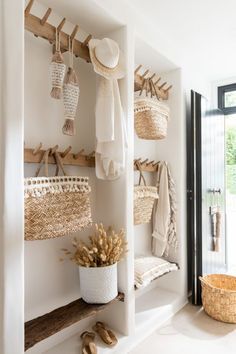 an entry way with baskets and clothes hanging on the wall