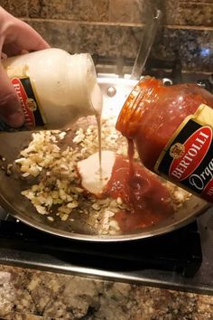 someone is pouring condiments into a pan full of food