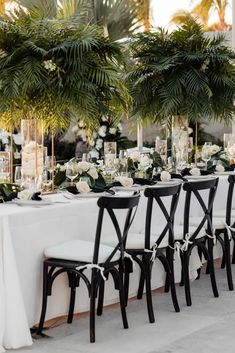 a long table with white flowers and greenery is set up for an outdoor wedding