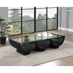 a glass coffee table sitting on top of a rug in front of a large window