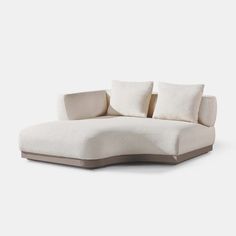 a white couch sitting on top of a wooden floor next to two pillow pillows in front of it