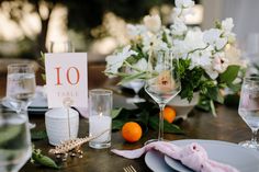 the table is set with white flowers and oranges for an elegant wedding reception or special event