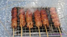 there are several meats on the grill with skewers coming out of them