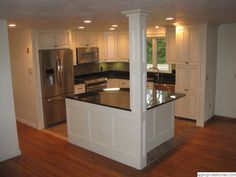 a kitchen with an island and stainless steel appliances in the center, along with hardwood floors