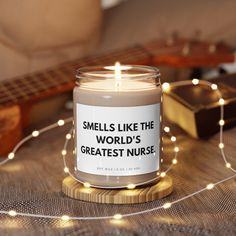 a candle that reads smells like the world's greatest nurse next to a guitar