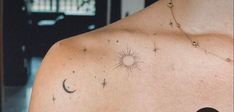 the back of a woman's shoulder with stars and moon tattoos on her chest