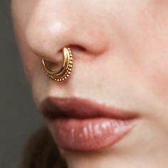 a close up of a person with a nose ring on their nose and one earring in the shape of a circle