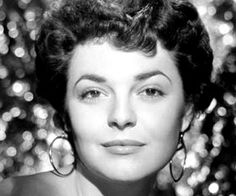 an old black and white photo of a woman with large earrings on her head, looking at the camera