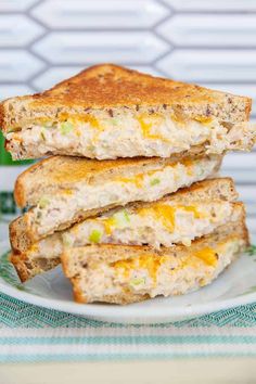 two sandwiches stacked on top of each other on a white plate next to a green cup