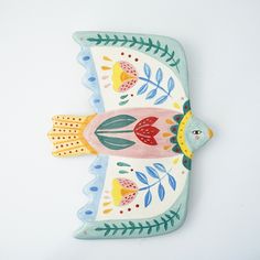 a ceramic bird decoration on a white surface with flowers and leaves painted on the wings