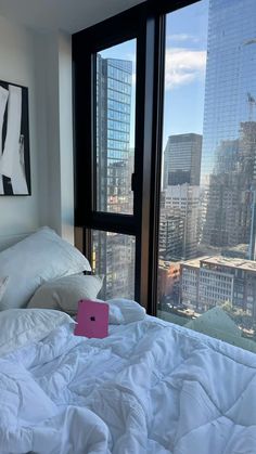 a laptop computer sitting on top of a bed in a bedroom next to a window