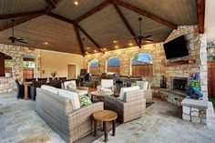 an outdoor living area with couches, chairs and a television mounted on the wall