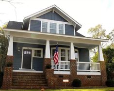 a blue and white house with an american flag on it's front porch,