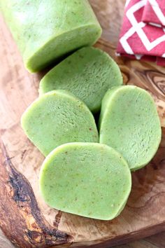 four pieces of green colored food on a wooden cutting board