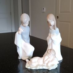 two white figurines sitting on top of a black counter next to a door