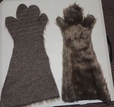 two pairs of gloves sitting on top of a white box with black and gray fur