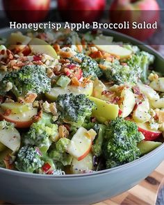 a close up of a bowl of food with broccoli and apples in the background