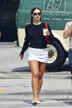 a woman walking down the street while holding a cup