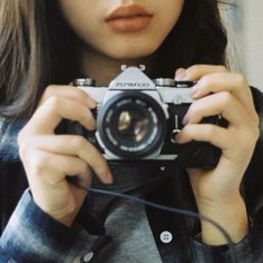 a woman holding up a camera to take a selfie in front of her face