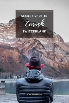 a person wearing a black jacket and red hat sitting in front of mountains with the words secret spot in zurich switzerland