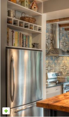 a kitchen with stainless steel appliances and wooden counter tops, along with open shelving