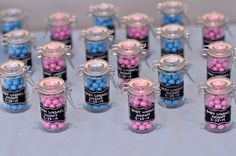 there are many small jars with candy in them on the table and one is filled with pink and blue candies