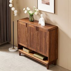 a wooden cabinet sitting next to a window with flowers in vases on top of it