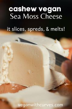 a person cutting cheese on top of a wooden board with text overlay that reads cashew vegan sea moss cheese it slices, spreads & melts