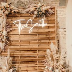 the sign is made out of wood and decorated with pampo leaves, dried flowers and greenery