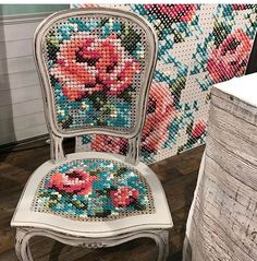 a white chair with flowers painted on the back and seat is sitting in front of a wall