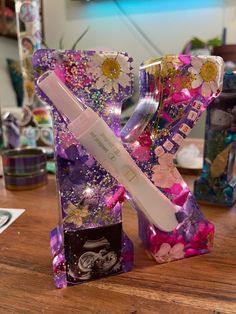 a toothbrush in the shape of a letter with flowers and glitters on it