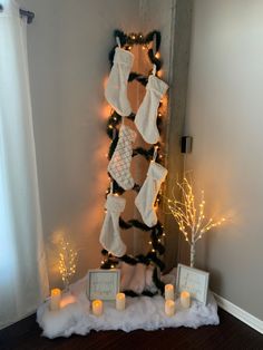 A ladder in the corner of an apartment, covered in garland and Christmas lights. Five white stockings are tacked on the ladder. The bottom of the ladder is surrounded by fake snow, light up birch trees, and holiday themed signs. Stocking With No Fireplace, Stalking Ideas For Christmas, Stocking Placement Without Fireplace, Christmas Stockings Without Fireplace, Stocking Organization, Creative Ways To Hang Stockings Without Mantle, Stocking Without Fireplace, Stockings No Fireplace Ideas