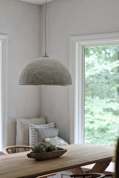 a dining room table with a bowl of succulents on it and two windows in the background