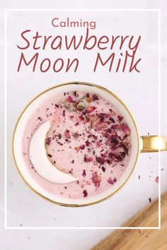 a white bowl filled with strawberry milk next to a wooden spoon