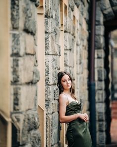 a woman leaning up against a stone wall