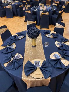 the table is set with blue and gold linens, silver place settings, and a black centerpiece