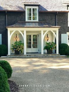 the front entrance to a large house with potted plants and lights on each side