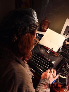 a man sitting at a desk writing on an old typewriter