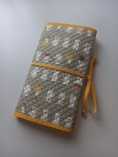 a small notebook covered in flowers and yellow ribbon on a white surface with a gray background