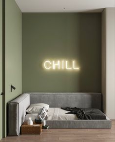 a bedroom with green walls and a grey couch in front of the wall that says chill