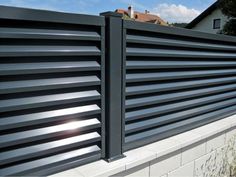 an aluminum fence with vertical slats on the top and bottom, in front of a house