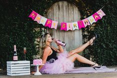 a woman is sitting on the ground drinking from a bottle while wearing heels and a pink tutu skirt