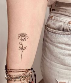 a woman's arm with a rose tattoo on the left side of her arm