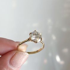 a person holding a gold ring with a diamond in it's center and the middle finger