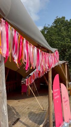 pink and orange streamers are hanging from the roof of a tent with surfboards